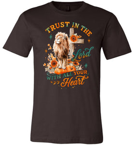 Brown t-shirt with a lion, cross, and pumpkin design with text 'Trust in the Lord with all your heart' on a white background.