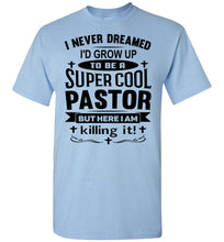 Load image into Gallery viewer, A light blue short-sleeve t-shirt with a black graphic text print on the front that reads 'I NEVER DREAMED I'D GROW UP TO BE A SUPER COOL PASTOR BUT HERE I AM killing it!'.