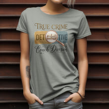 Load image into Gallery viewer, Person wearing a t-shirt with 'True Crime Detective Couch Division' design against a wooden slat background