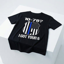 Load image into Gallery viewer, A black short-sleeve t-shirt displayed on a white geometric pedestal. The shirt features a graphic design with the text '10-78?' and 'I GOT YOUR 6' in white, surrounding a shield emblem with a vertical blue stripe and an American flag motif.