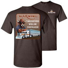 Load image into Gallery viewer, Brown t-shirt with a graphic of a bull and truck, and text &#39;Warning: Tailgaters will be fertilized&#39;.