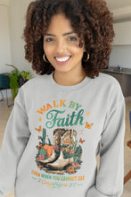 Load image into Gallery viewer, Woman wearing a gray sweatshirt with &#39;Walk by Faith&#39; design in a kitchen.