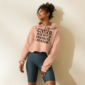 Woman wearing a peach hoodie with text and dark shorts against a plain background